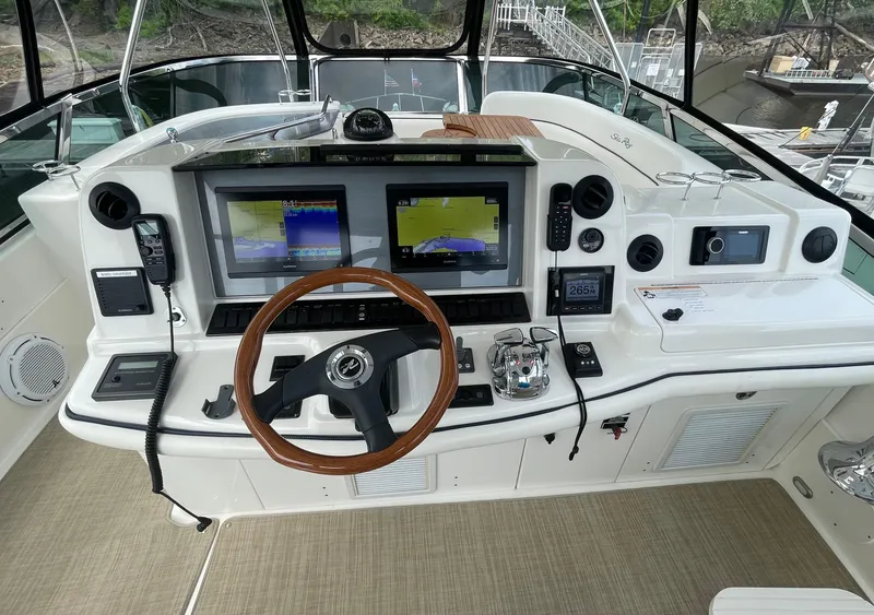 Slide: The Image of 2005 Sea Ray 500 Sedan Bridge helm with dual navigation screens and wooden steering wheel. - 36