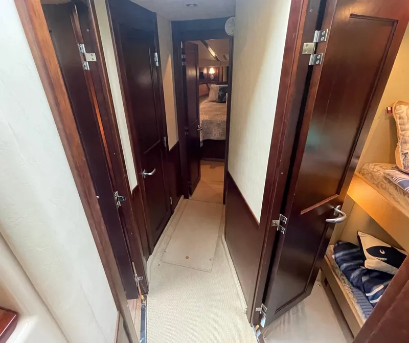 Slide: The Image of Interior hallway of 2005 Sea Ray 500 Sedan Bridge yacht with wooden doors and cozy bedding. - 47