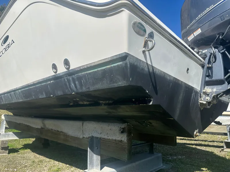Slide: The Image of 2018 Cobia 220 Center Console boat on a stand, showing hull and outboard motor. - 10