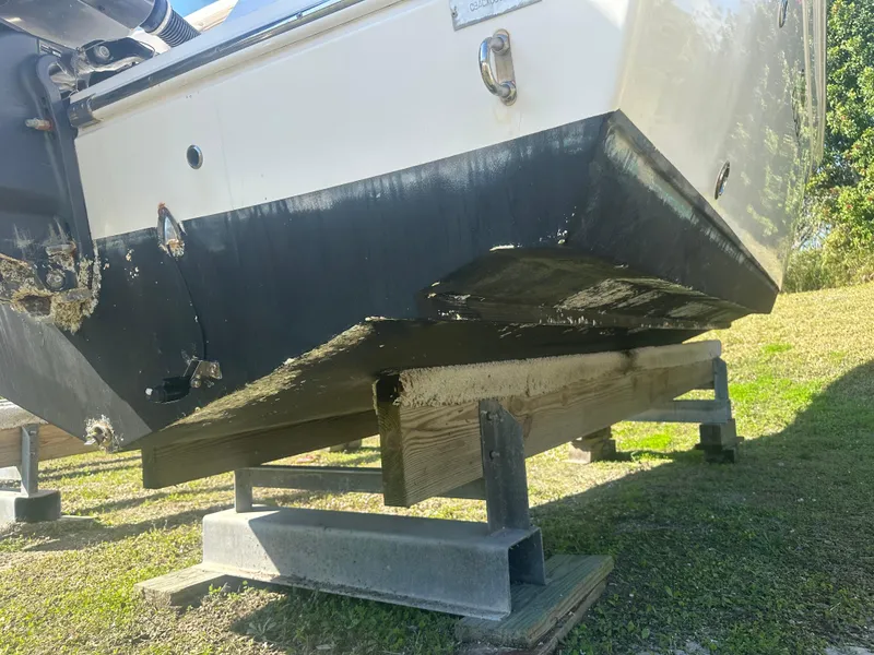 Slide: The Image of 2018 Cobia 220 Center Console boat on wooden supports, showing hull condition. - 11