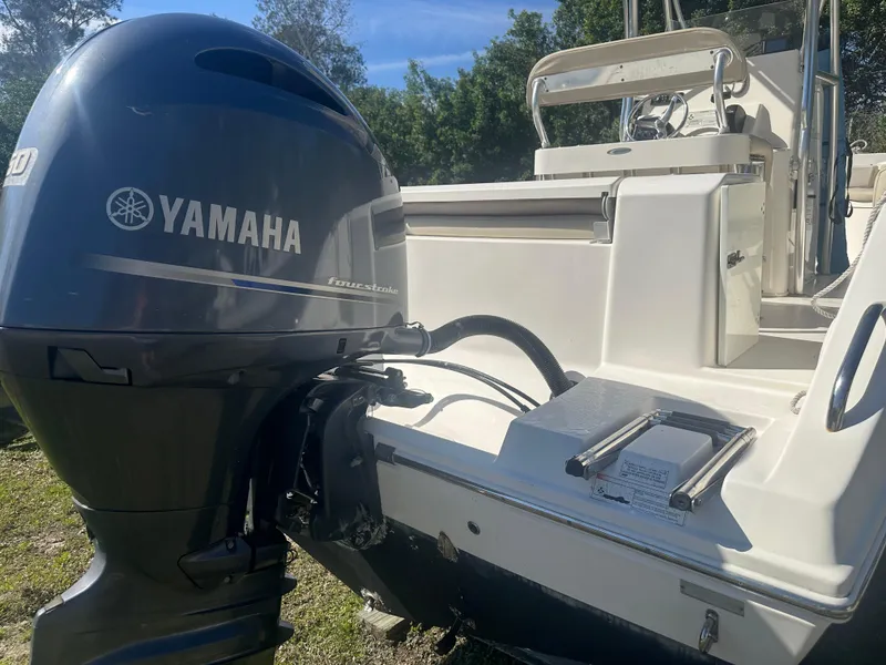 Slide: The Image of 2018 Cobia 220 Center Console with Yamaha outboard motor, parked on grass. - 13