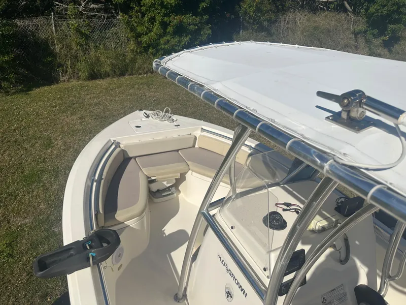 Slide: The Image of 2018 Cobia 220 Center Console boat with seating and T-top, parked on grass. - 23
