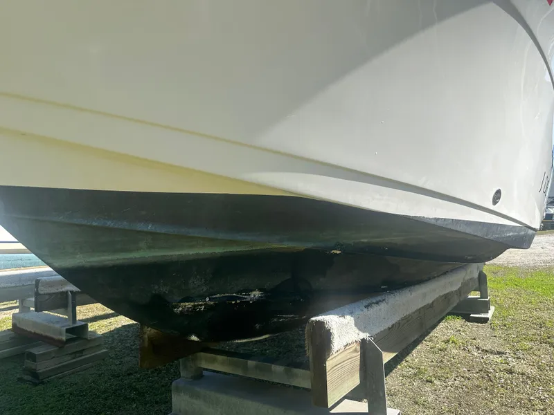 Slide: The Image of 2018 Cobia 220 Center Console boat hull on wooden supports, outdoor setting. - 9