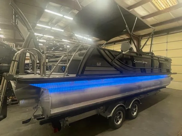 Slide: The Image of 2025 South Bay 500 pontoon boat with blue LED lights in a warehouse setting. - 2