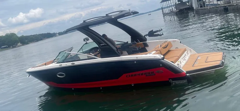 The Image of 2025 Chaparral 28 Surf boat on calm water near a dock. - 0