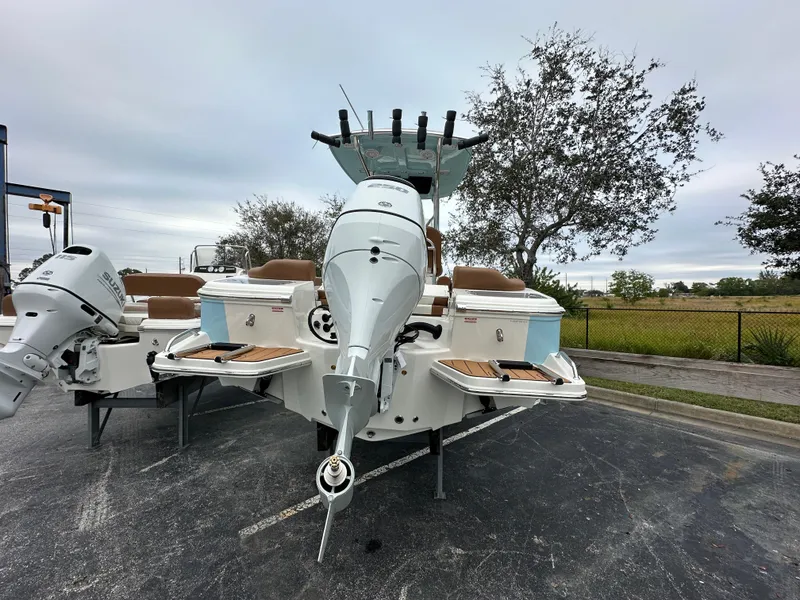 Slide: The Image of 2025 Pioneer 222 Islander boat with outboard motor, parked outdoors on a cloudy day. - 2