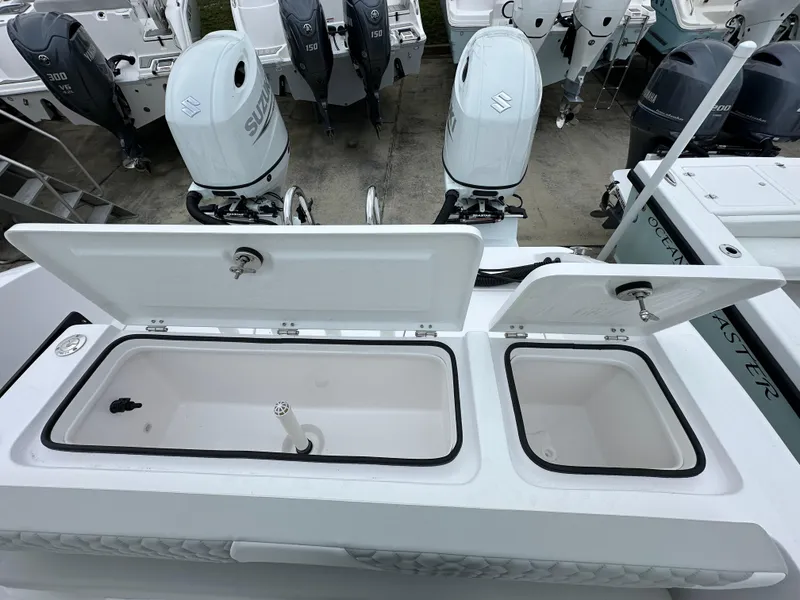 Slide: The Image of 2025 Twin Vee 240 GFX CC boat with open storage compartments and dual outboard engines. - 14