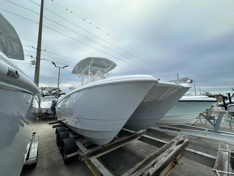 Slide: The Image of 2025 Twin Vee 240 GFX CC boat on trailer, displayed outdoors under cloudy sky. - 2