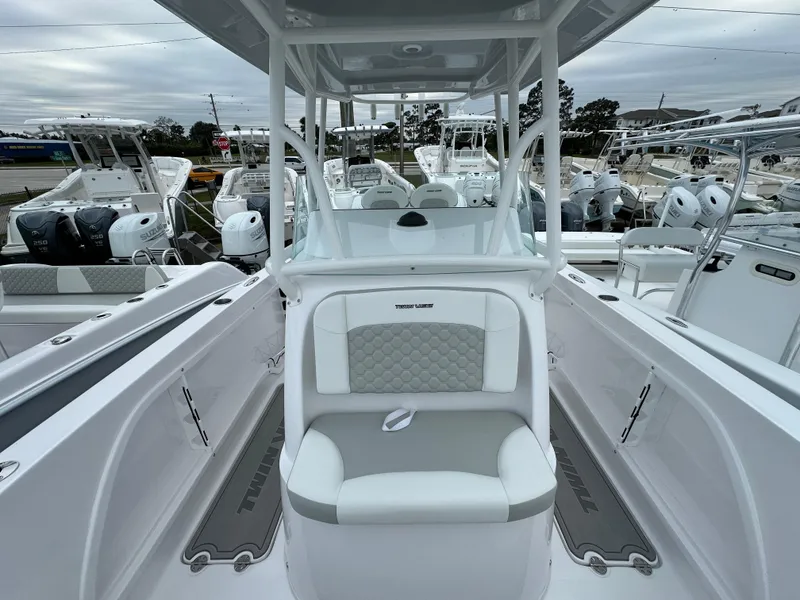 Slide: The Image of 2025 Twin Vee 240 GFX CC boat interior with seating and console, surrounded by other boats. - 9