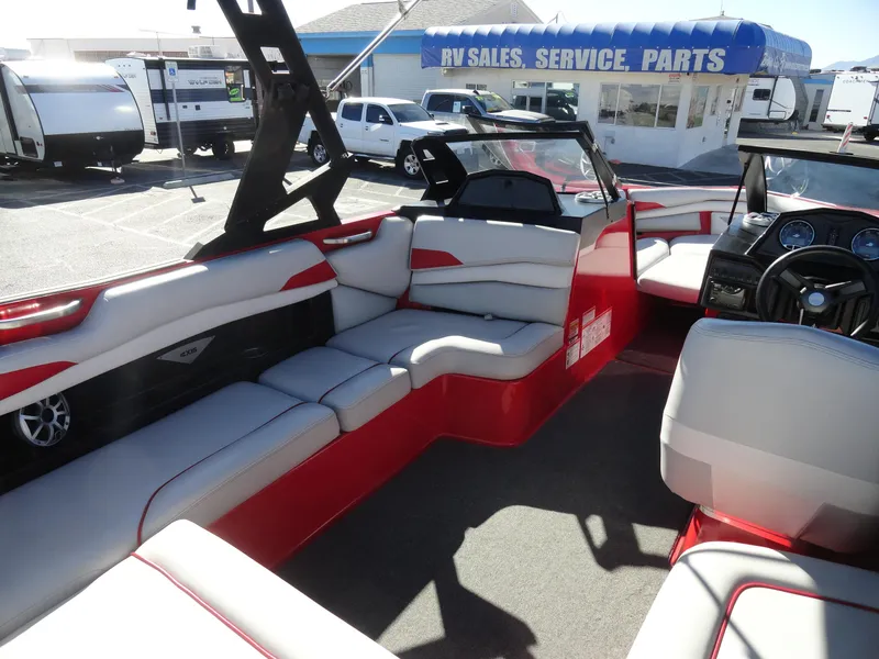 Slide: The Image of 2016 Axis A22 boat interior with red and white seating, parked near RV sales. - 18
