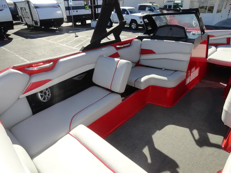 Slide: The Image of 2016 Axis A22 boat interior with red and white seating, parked in a lot. - 19