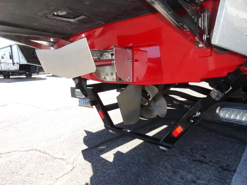 Slide: The Image of 2016 Axis A22 boat propeller and rudder detail, red hull, parked on trailer. - 28