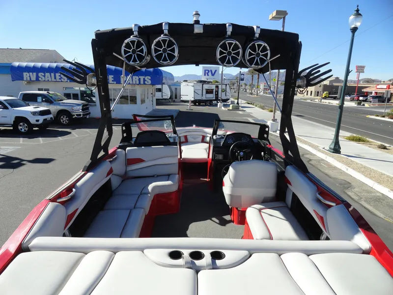 Slide: The Image of 2016 Axis A22 boat interior with red and white seating, parked near RV sales. - 9