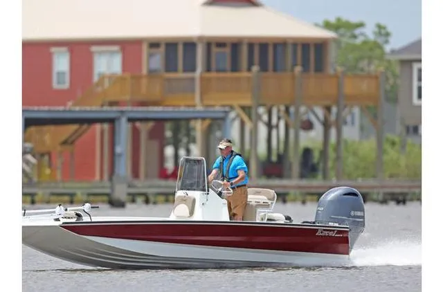 Slide: The Image of 2022 Excel Bay Pro 203 boat cruising on water near waterfront homes. - 24