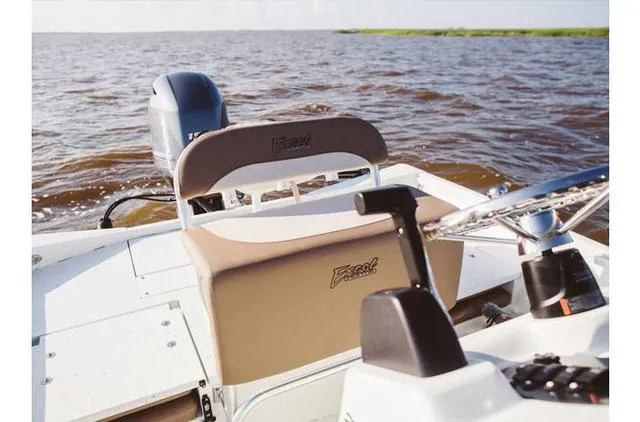 Slide: The Image of 2022 Excel Bay Pro 203 boat interior with steering wheel and seating, on open water. - 30