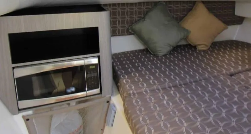 Slide: The Image of 2016 World Cat 2780 Glacier Bay Edition interior with microwave and cozy bedding. - 37