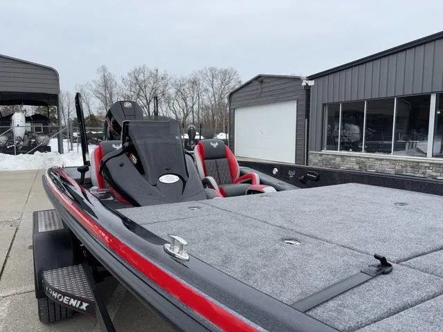 Slide: The Image of 2025 Phoenix 921 ELITE bass boat with red accents, parked outdoors near a building. - 9