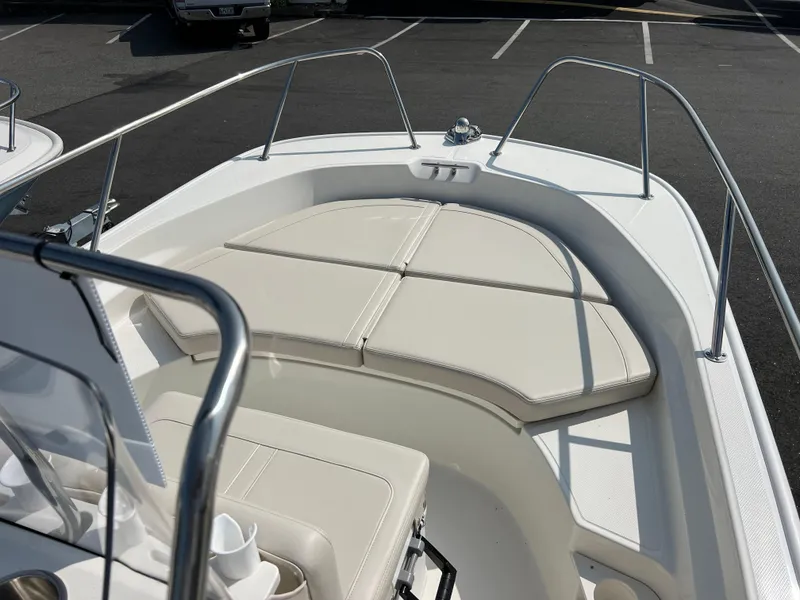 Slide: The Image of 2025 Boston Whaler 170 Montauk boat interior with cushioned seating in a parking lot. - 11