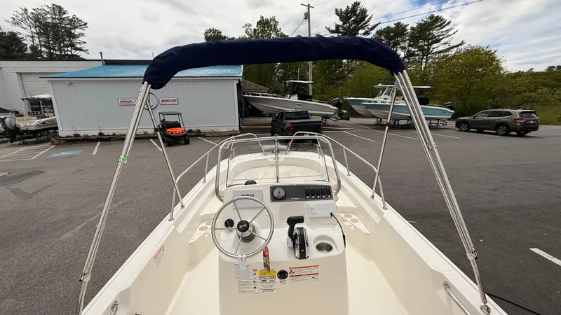 Slide: The Image of 2025 Boston Whaler 170 Montauk boat with canopy, parked in a marina lot. - 4