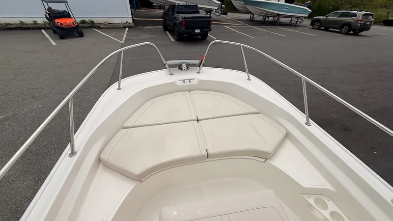 Slide: The Image of 2025 Boston Whaler 170 Montauk boat interior with cushioned seating in a parking lot. - 5
