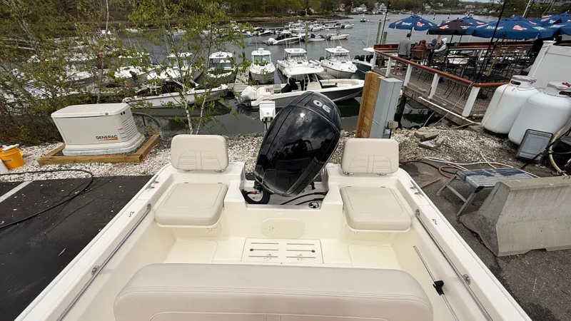 Slide: The Image of 2025 Boston Whaler 170 Montauk boat docked, showcasing seating and motor, with marina in background. - 6