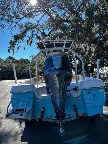Slide: The Image of 2024 NauticStar 231 Hybrid boat with outboard motor, parked under a tree on a sunny day. - 3