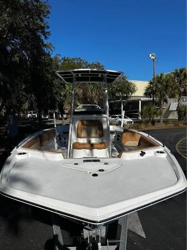 Slide: The Image of 2024 NauticStar 231 Hybrid boat with sleek design, parked outdoors under clear blue sky. - 4