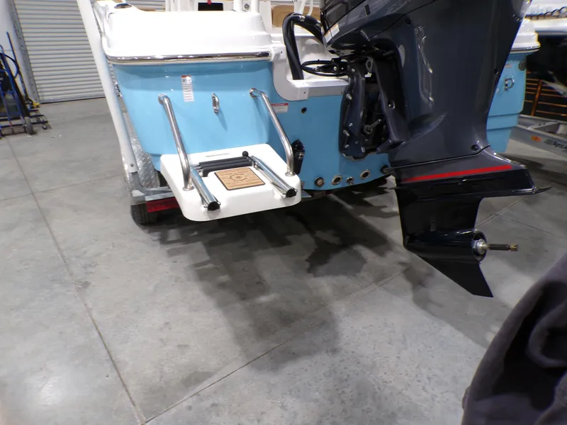 Slide: The Image of 2024 NauticStar 231 Hybrid boat with outboard motor and swim platform in a garage. - 7