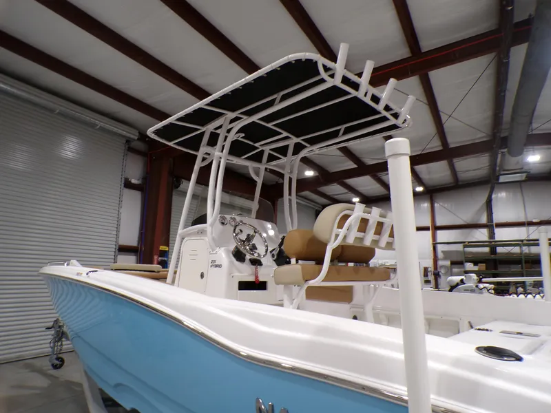 Slide: The Image of 2024 NauticStar 231 Hybrid boat in a warehouse, featuring a blue hull and T-top. - 9