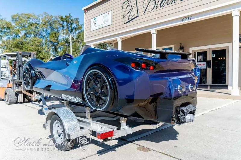 Slide: The Image of 2023 Watersports Car SERIES X JET CAR BOAT on trailer outside a marine shop. - 2