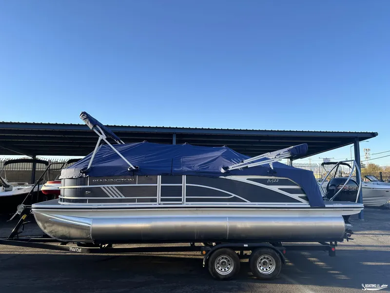 Slide: The Image of 2025 Bennington M22 pontoon boat on trailer, covered and parked outdoors. - 4