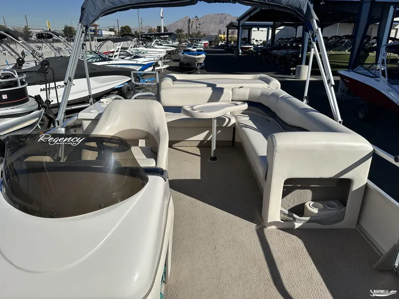 Slide: The Image of 2005 Sun Tracker PARTY BARGE 25 interior with seating and table, parked among other boats. - 7