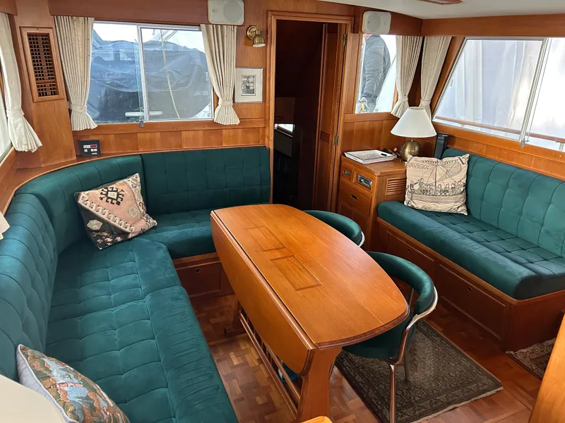 Slide: The Image of Interior of a 1999 Grand Banks Classic yacht with green seating and wooden table. - 1