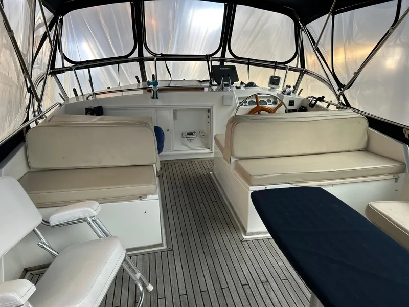Slide: The Image of 1999 Grand Banks Classic boat interior with seating and helm, featuring a covered deck area. - 24