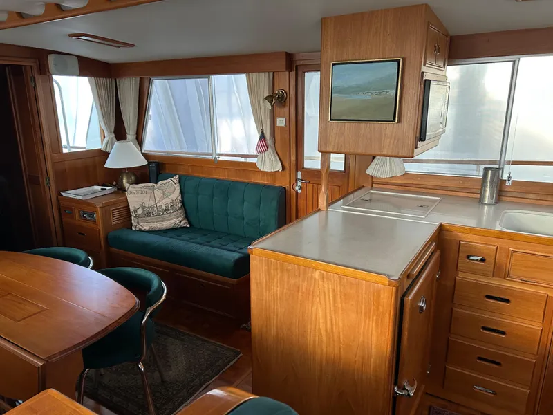 Slide: The Image of Interior of a 1999 Grand Banks Classic yacht with wood furnishings and green seating. - 4