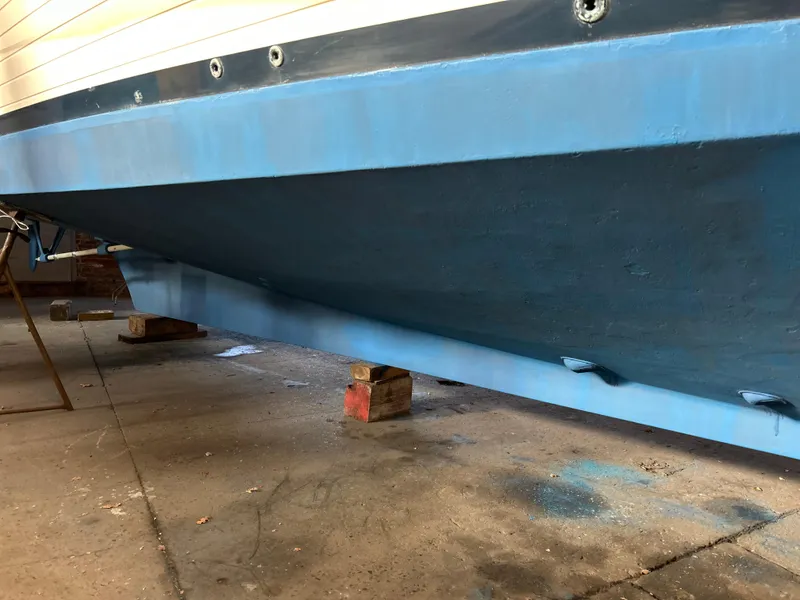 Slide: The Image of 1999 Grand Banks Classic boat hull in dry dock, showing blue paint and support blocks. - 40