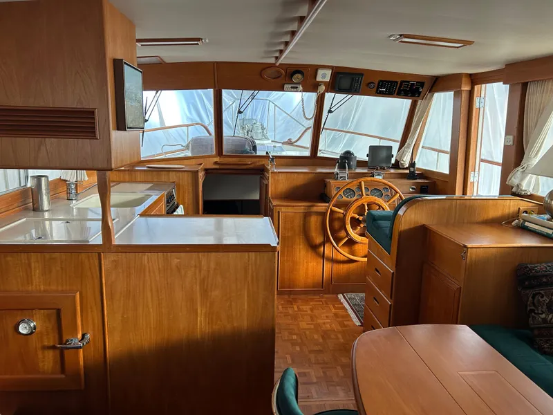 Slide: The Image of Interior of a 1999 Grand Banks Classic yacht, featuring a wooden helm and cozy seating area. - 7