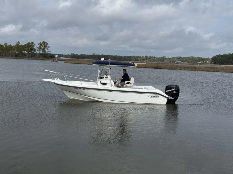 Slide: The Image of 1999 Boston Whaler 23 Outrage boat cruising on a calm lake under cloudy skies. - 4
