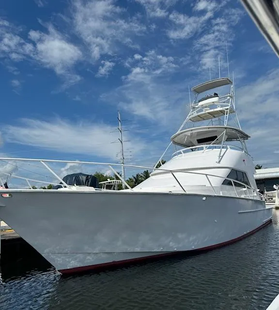 Slide: The Image of 1990 Striker Sportfish yacht docked under a clear blue sky. - 1