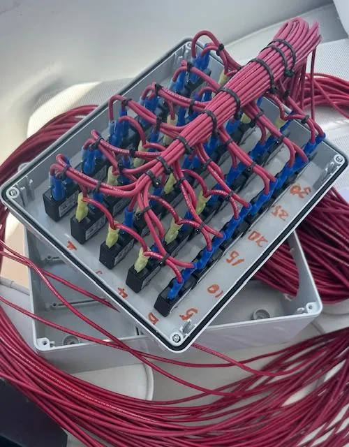 Slide: The Image of Electrical wiring box with red cables in a 1990 Striker Sportfish boat. - 18