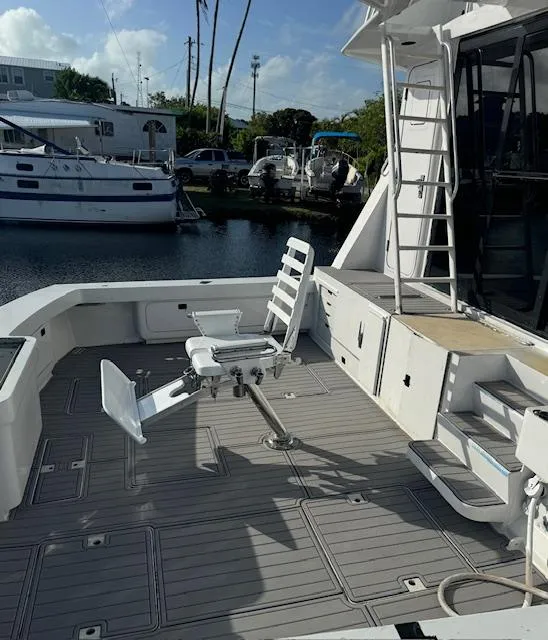 Slide: The Image of 1990 Striker Sportfish boat deck with fishing chair, docked near other boats. - 2