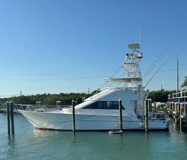 Slide: The Image of 1990 Striker Sportfish boat docked in calm waters under clear blue sky. - 23