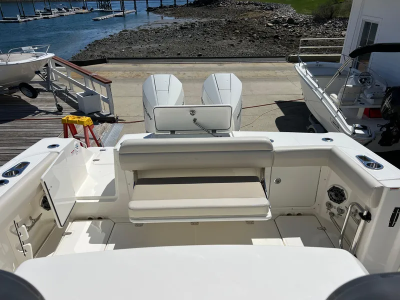 Slide: The Image of 2025 Boston Whaler 330 Outrage boat with dual engines docked by the shore. - 6