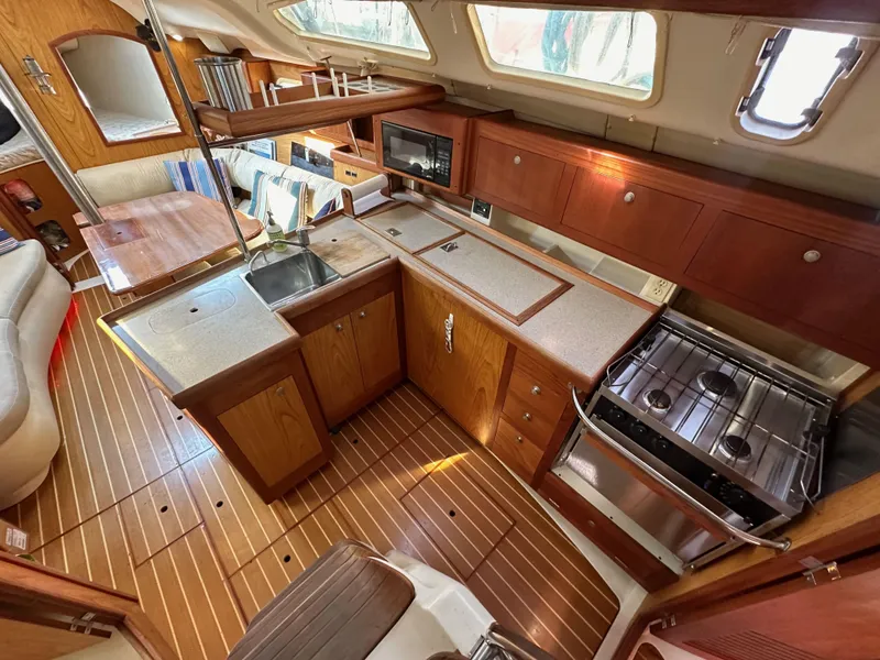 Slide: The Image of 2001 Hunter 380 yacht interior with wooden cabinetry, kitchen, and seating area. - 22