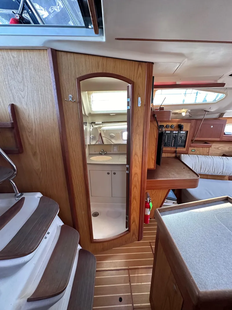 Slide: The Image of Interior of 2001 Hunter 380 sailboat, featuring wooden cabinetry and compact bathroom. - 30