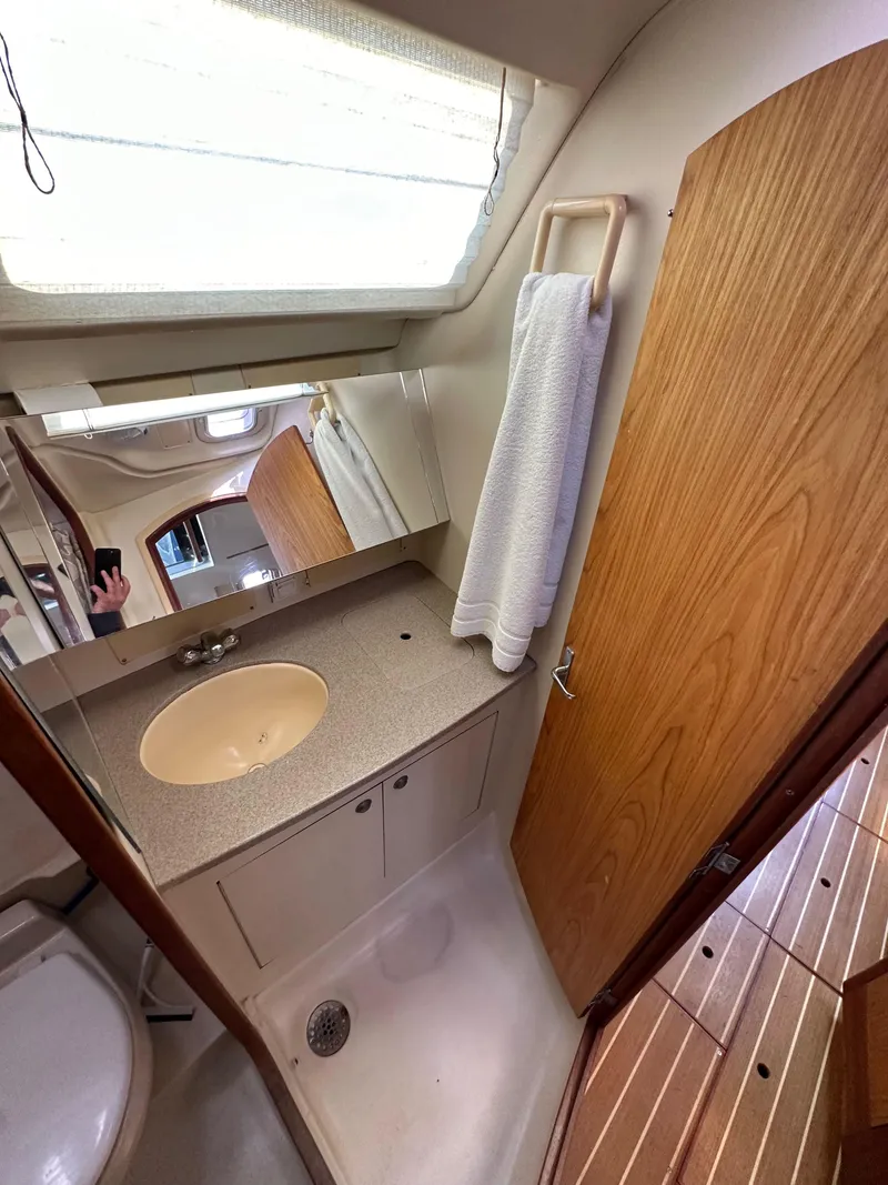 Slide: The Image of 2001 Hunter 380 yacht bathroom with sink, mirror, and wooden cabinetry. - 33