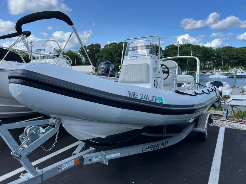 Slide: The Image of 2022 Ribcraft 5.85 boat on trailer, parked at marina under blue sky. - 0