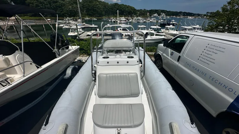 Slide: The Image of 2022 Ribcraft 5.85 inflatable boat docked near marina with multiple boats. - 1