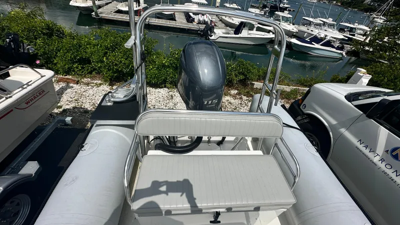 Slide: The Image of Ribcraft 5.85 boat, 2022 model, with outboard motor, docked near other boats and vehicles. - 2