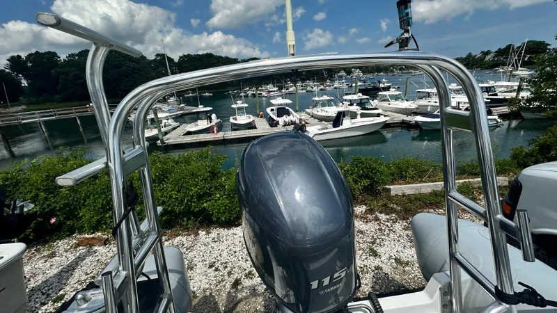 Slide: The Image of 2022 Ribcraft 5.85 boat with 115 HP engine, docked at a marina under a blue sky. - 6